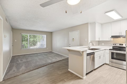 an empty kitchen and living room with white cabinets and a window